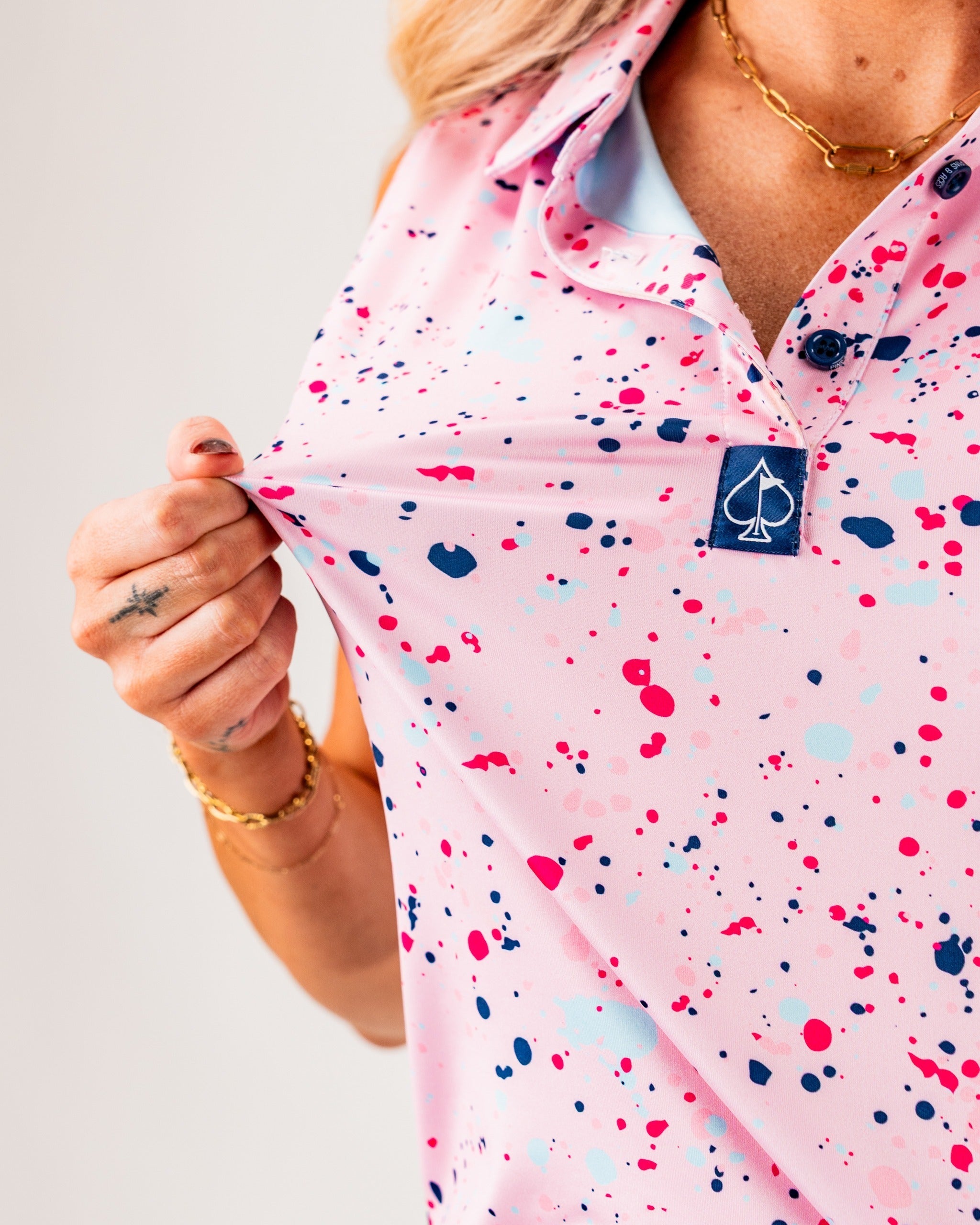 Women's pink splatter golf polo featuring colorful paint splashes, designed for a bold and stylish look on the course.