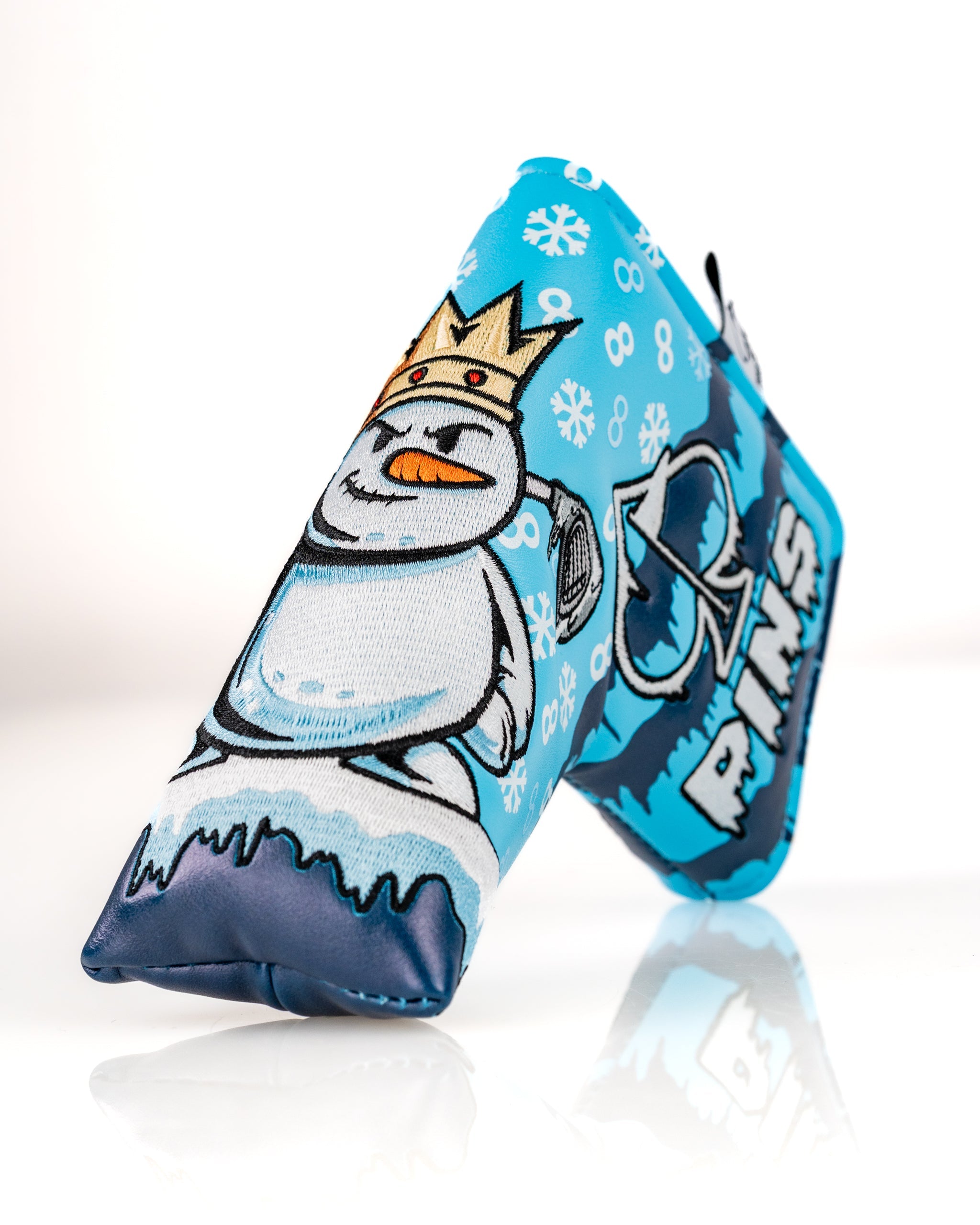 Snowman blade putter cover featuring a playful design with a crowned snowman and snowflake patterns in blue.