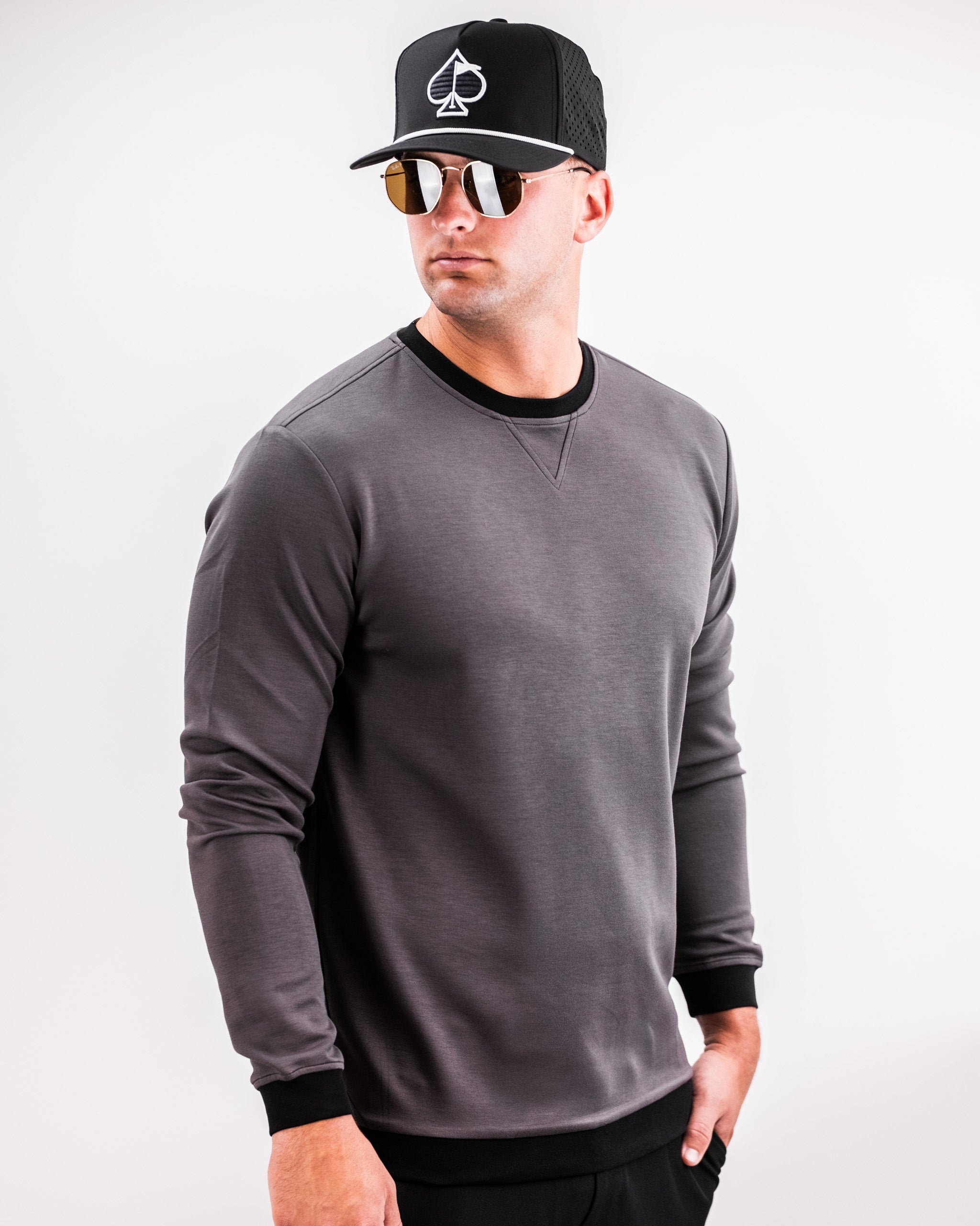 Male model wearing a slate grey Player Preferred™ Crewneck with black cuffs, black neckline, black cap, and sunglasses.