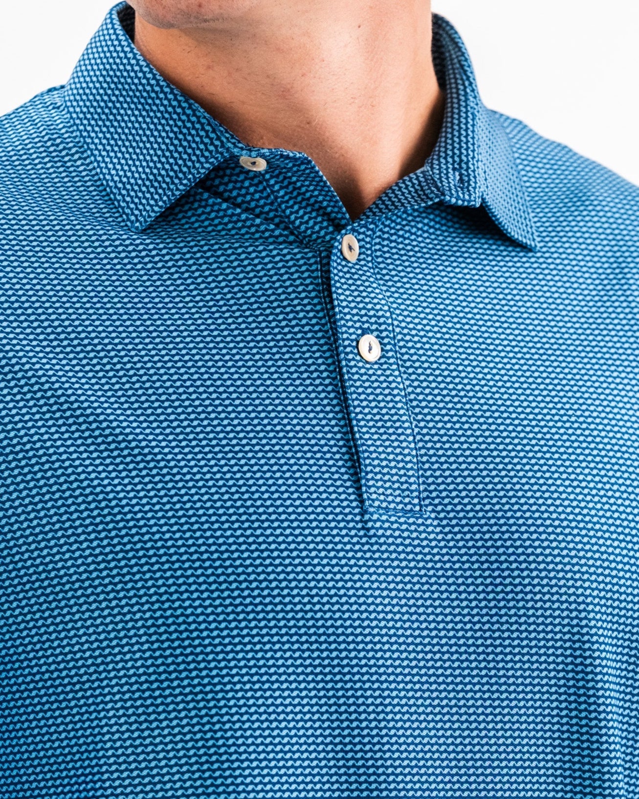 Close-up of a blue Player Preferred™ Polo shirt with a wave-like pattern, featuring a collar and white buttons.
