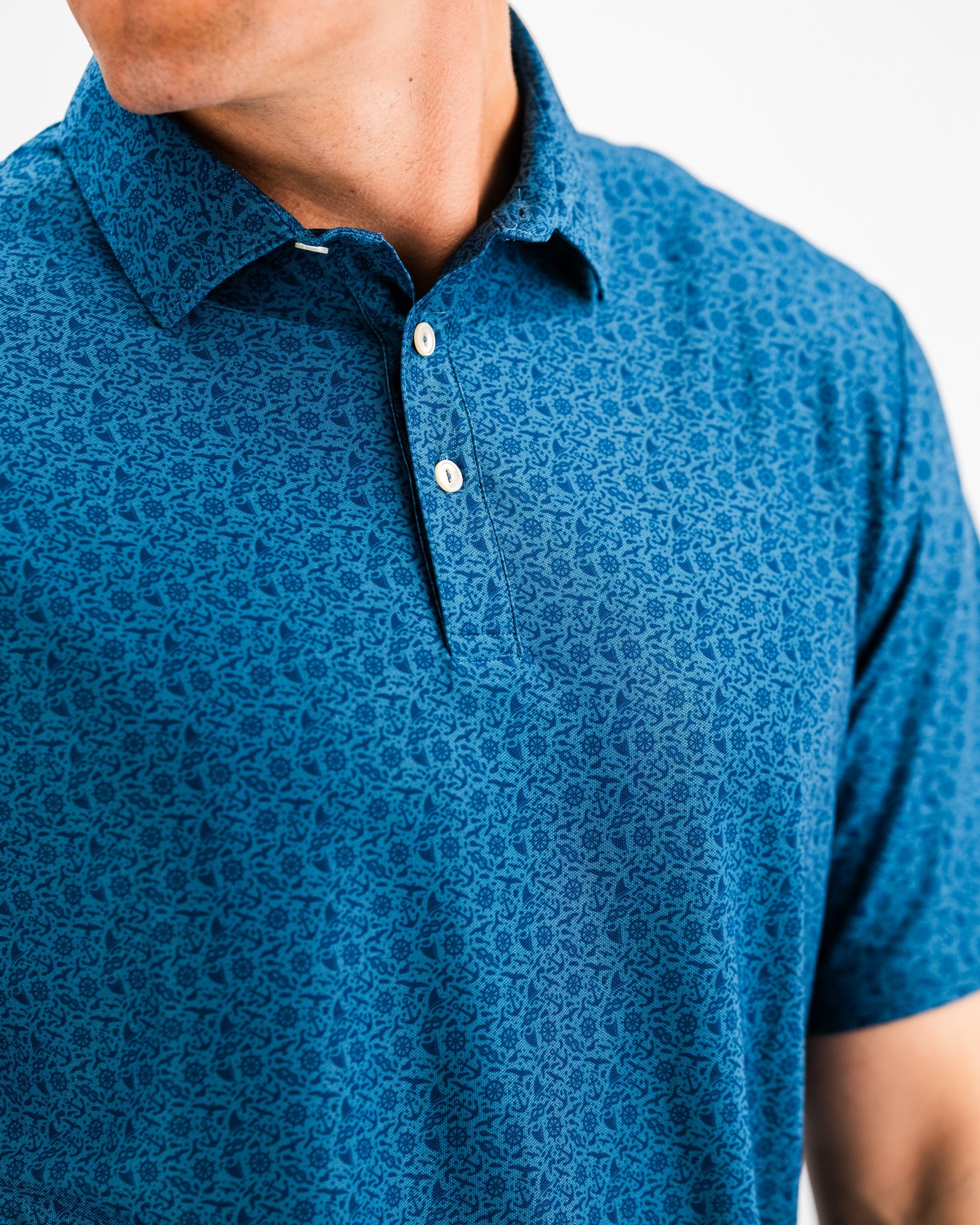 Player Preferred™ Polo - The Mariner, featuring a navy blue design with a classic collar and short sleeves, displayed on a wooden background.