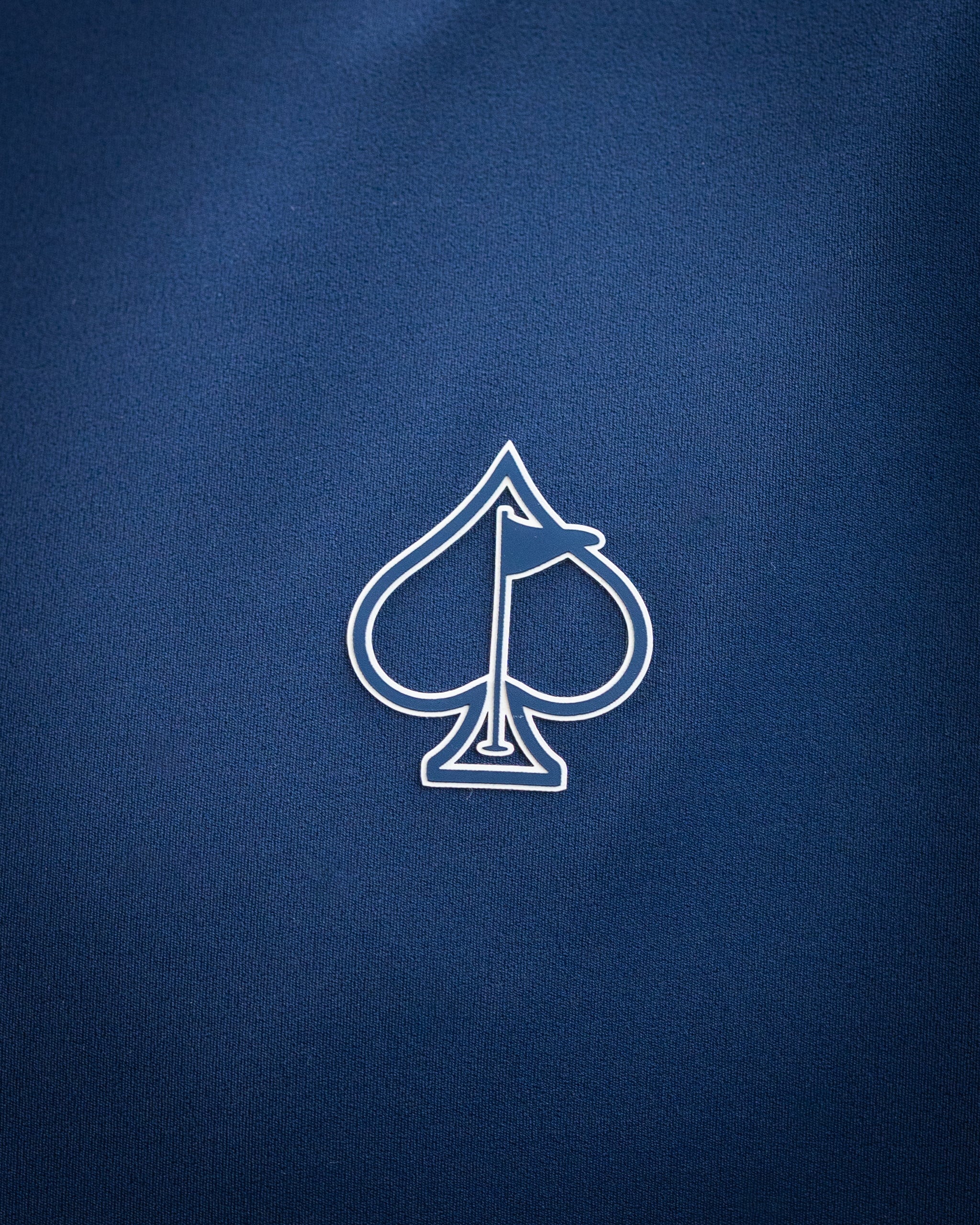 Close-up of a navy blue golf accessory with a white spade and flag logo, highlighting bold, unique design for standout gol...