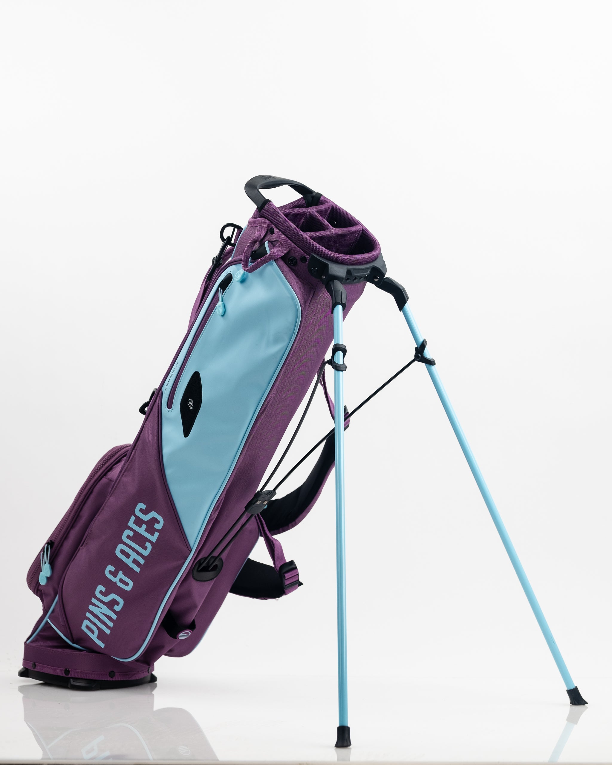 Colorful purple and light blue golf stand bag with bold "PINS & ACES" branding, featuring multiple compartments and adjust...