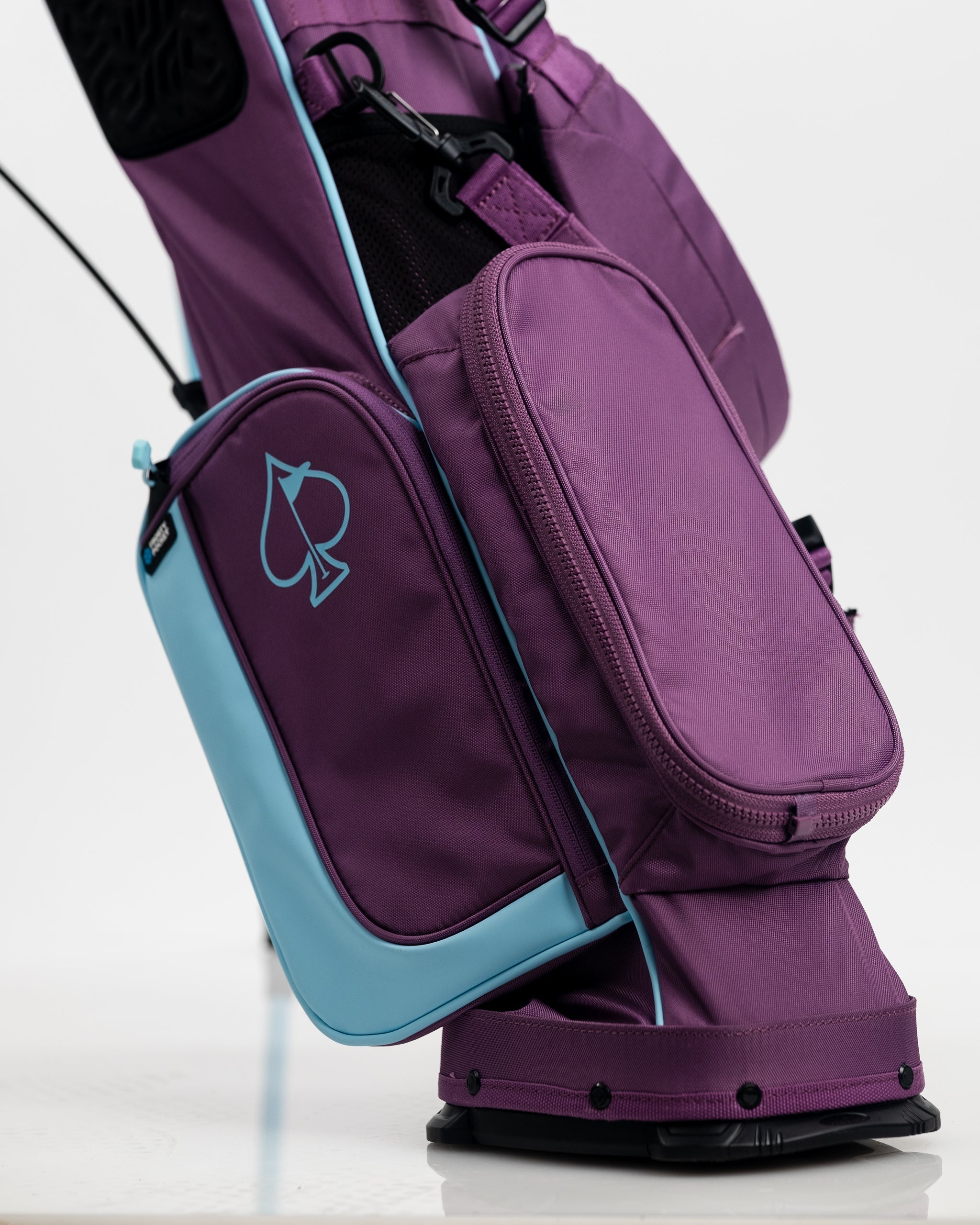 Bold purple and light blue golf bag with a spade logo, multiple compartments, and sporty design for standout golf style.