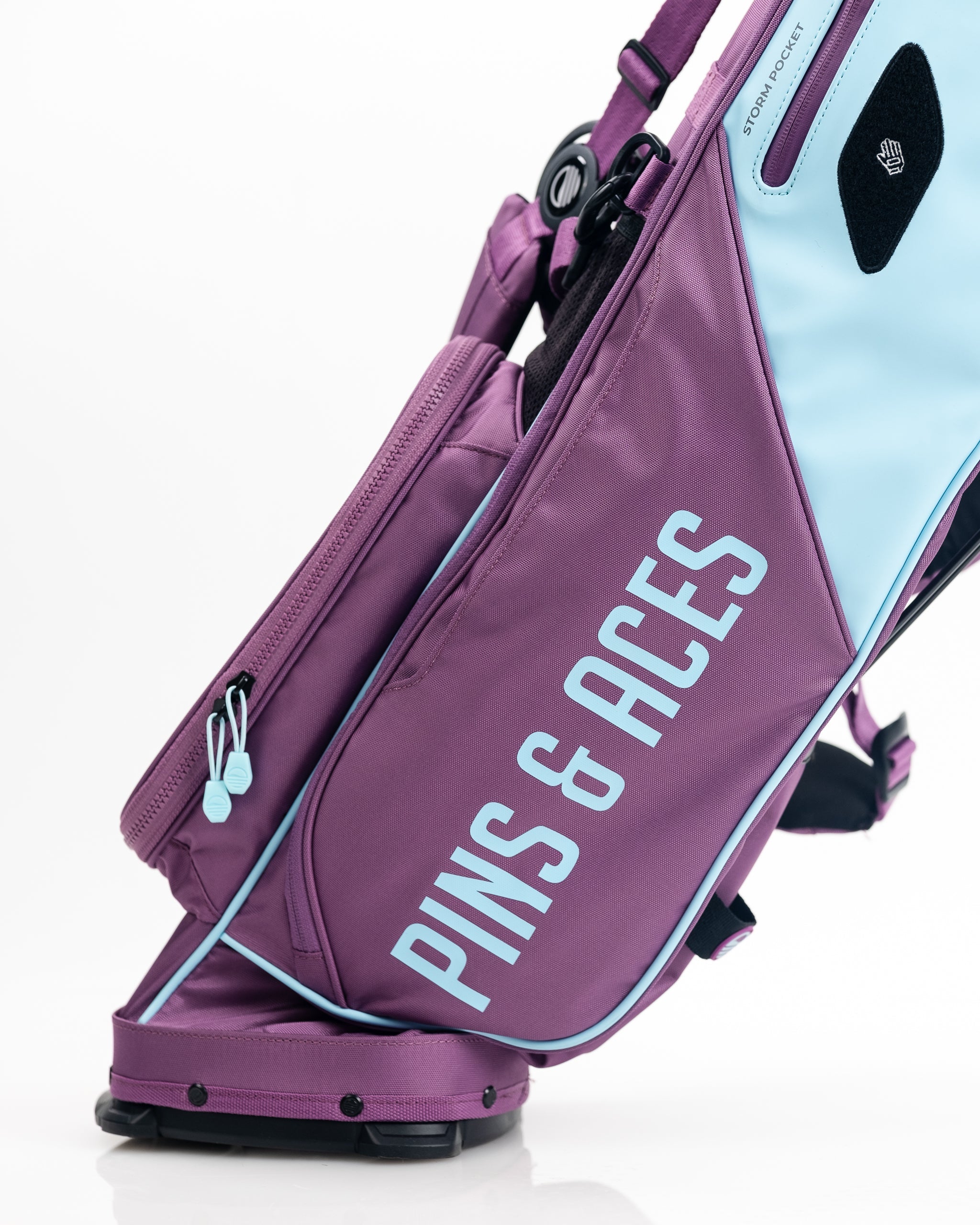 Colorful purple and light blue golf bag with bold "PINS & BUNCH" text, designed for standout golf apparel and accessories.