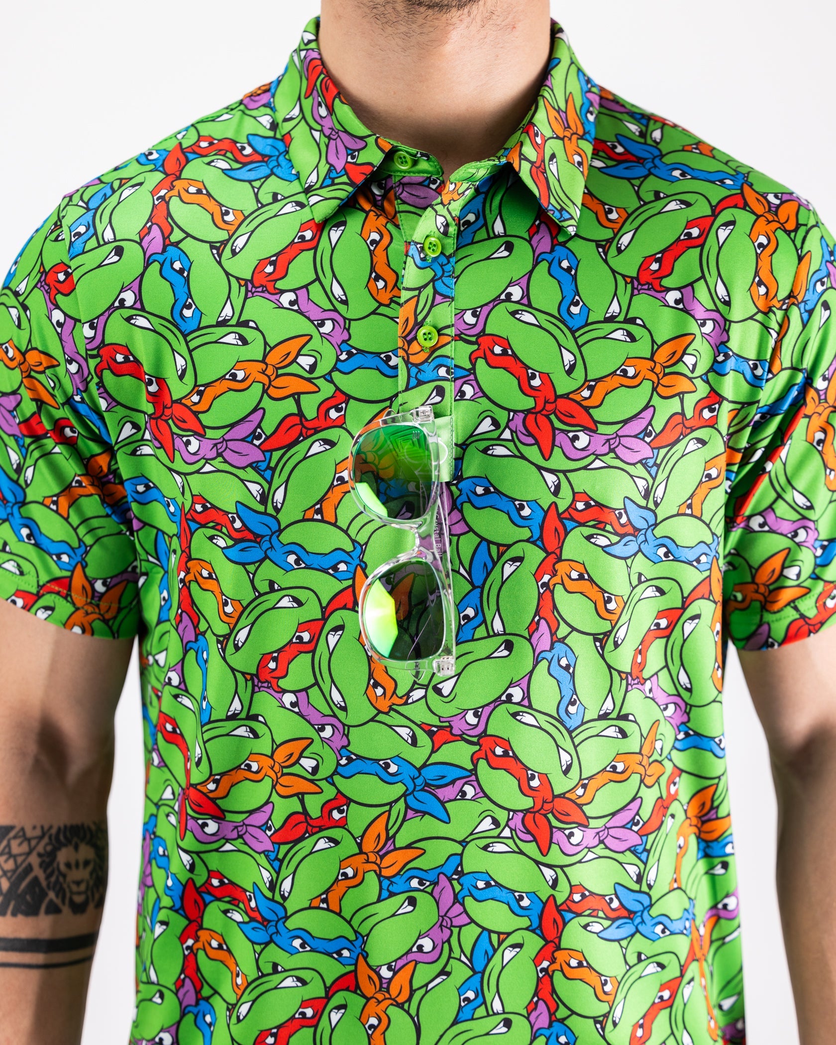 TMNT Mean Green polo shirt featuring the iconic Teenage Mutant Ninja Turtles' faces in vibrant colors.