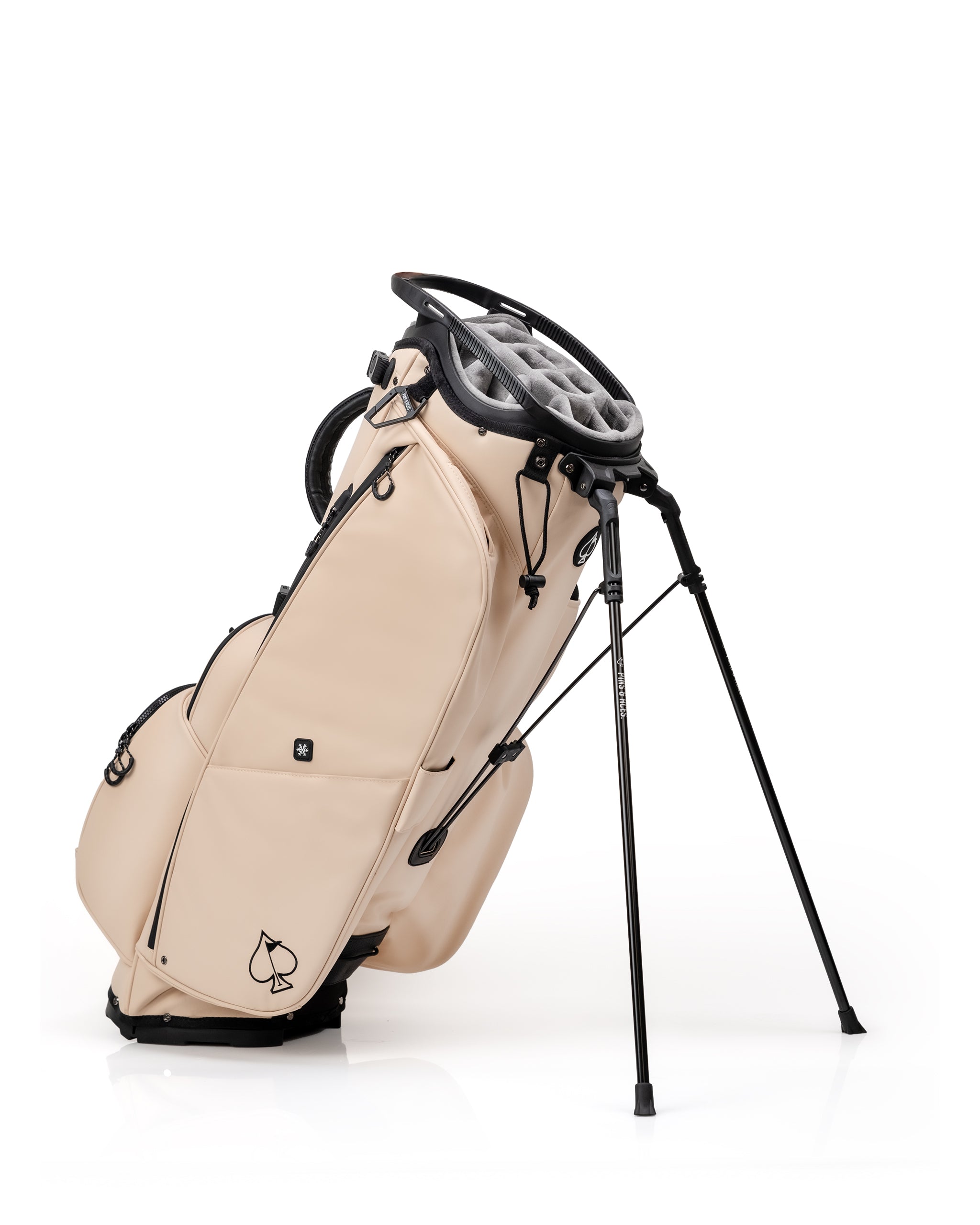 Golf bag with beige exterior, black accents, and a spade logo, featuring multiple pockets, stand, and soft gray interior.