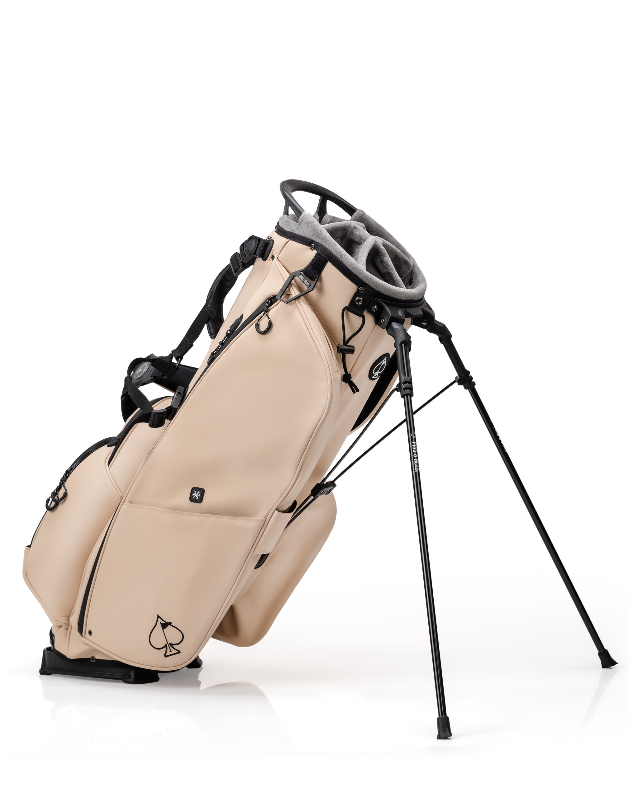 Beige golf bag with black accents and a spade logo, featuring multiple pockets and a stand, perfect for bold golf style.