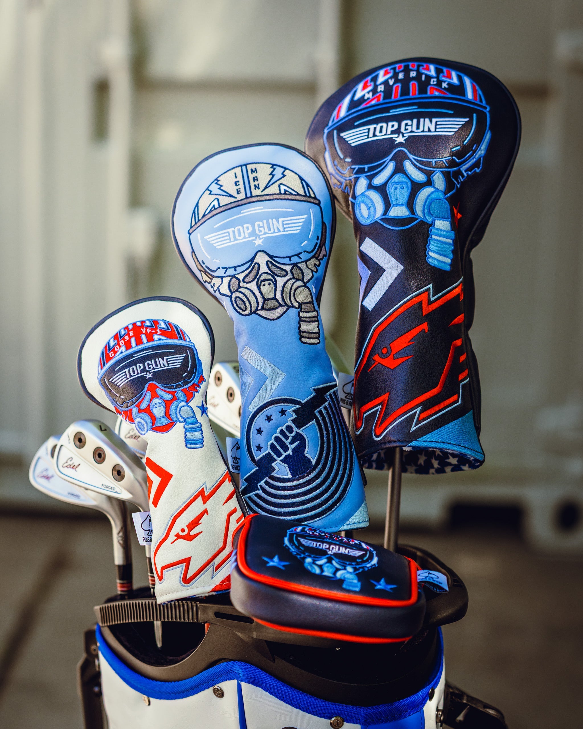 Set of Top Gun themed golf headcovers featuring a pilot helmet design with goggles, in black, blue, and white colors.
