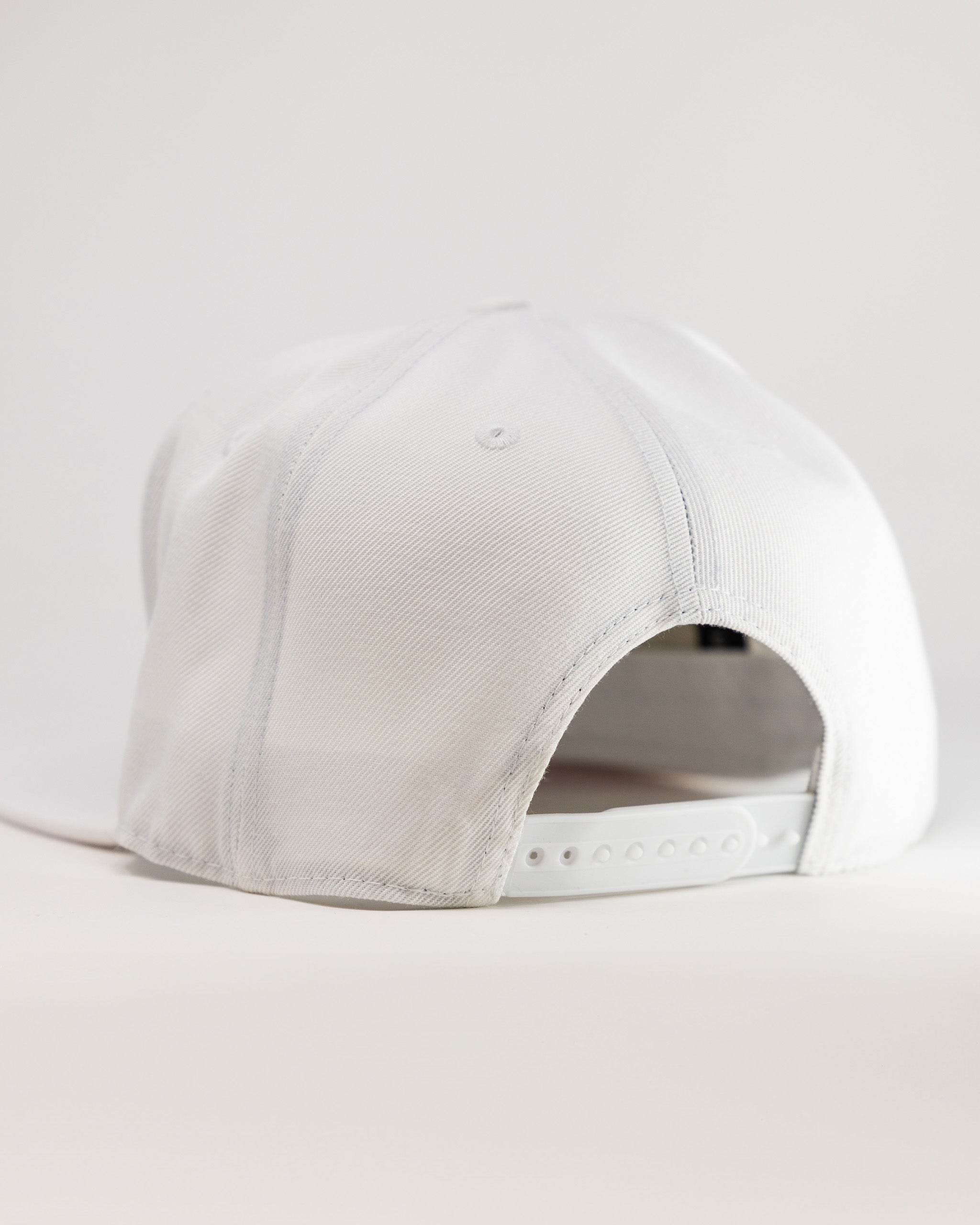 White golf cap with adjustable strap, clean design, and subtle stitching for bold golf style. Perfect for standing out on ...