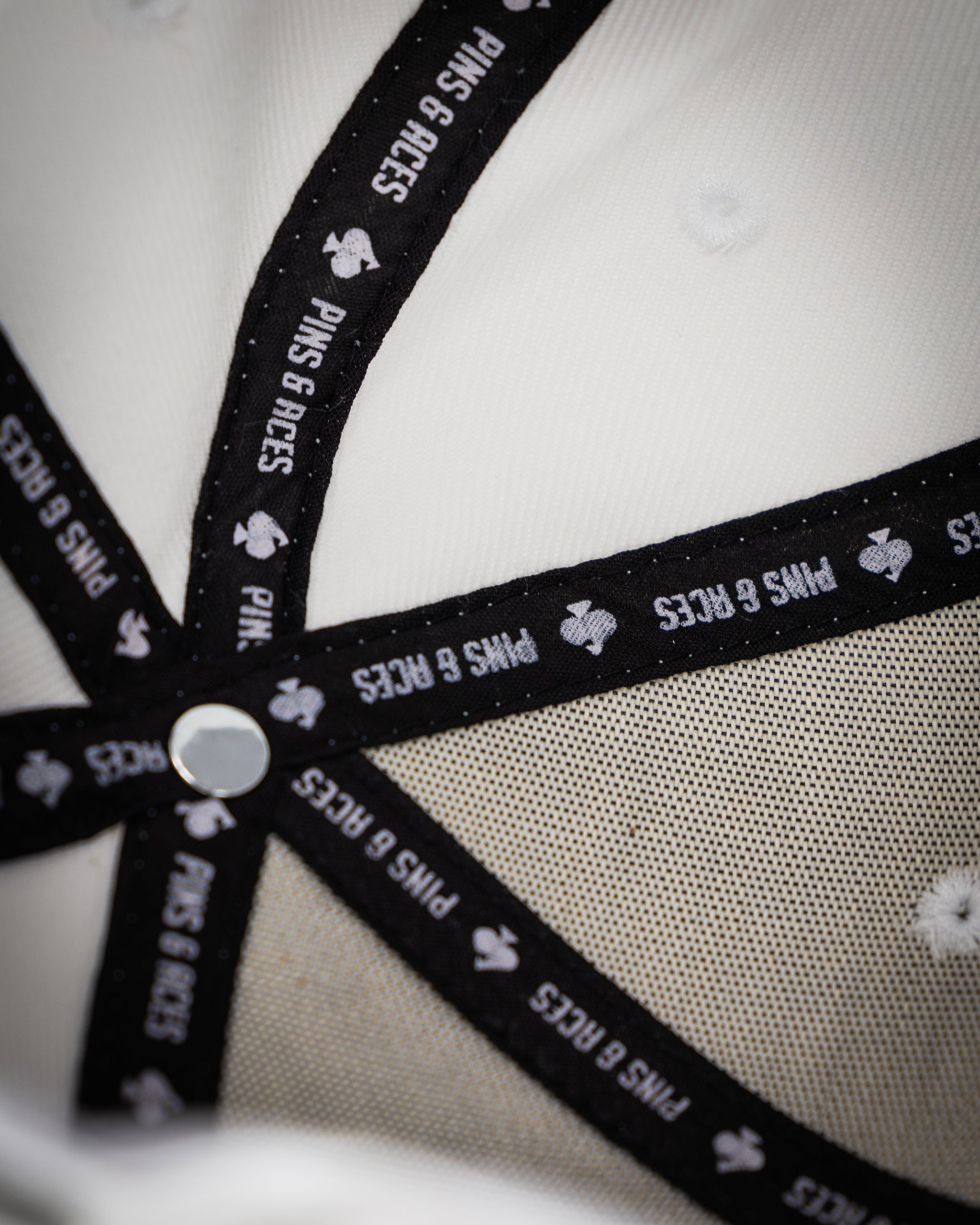 Close-up of a golf headcover with black trim, white fabric, and "PINS & ACES" branding for bold, unique golf style.