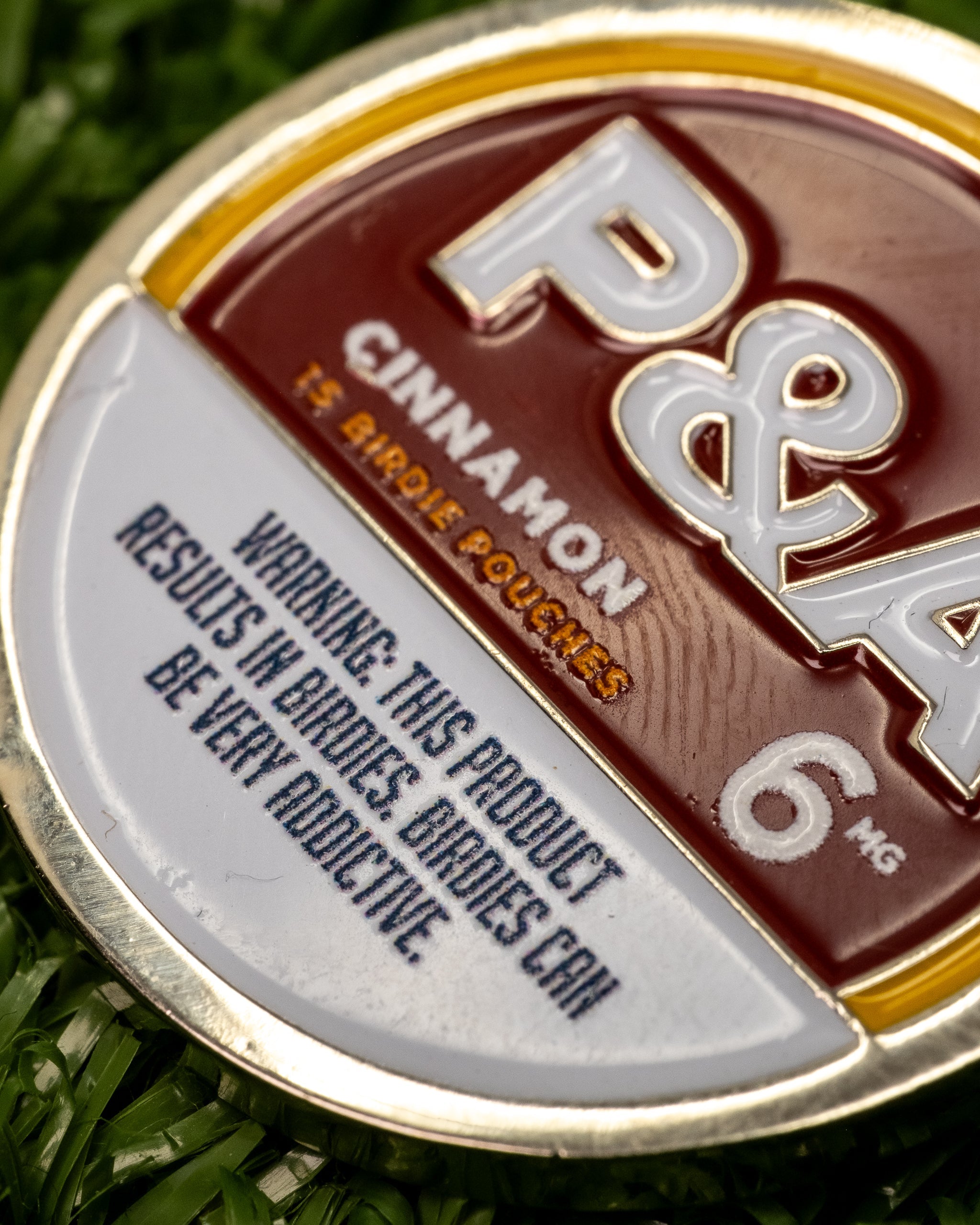Close-up of a 6 Milly cinnamon ball marker, featuring a warning about addiction and branding details.