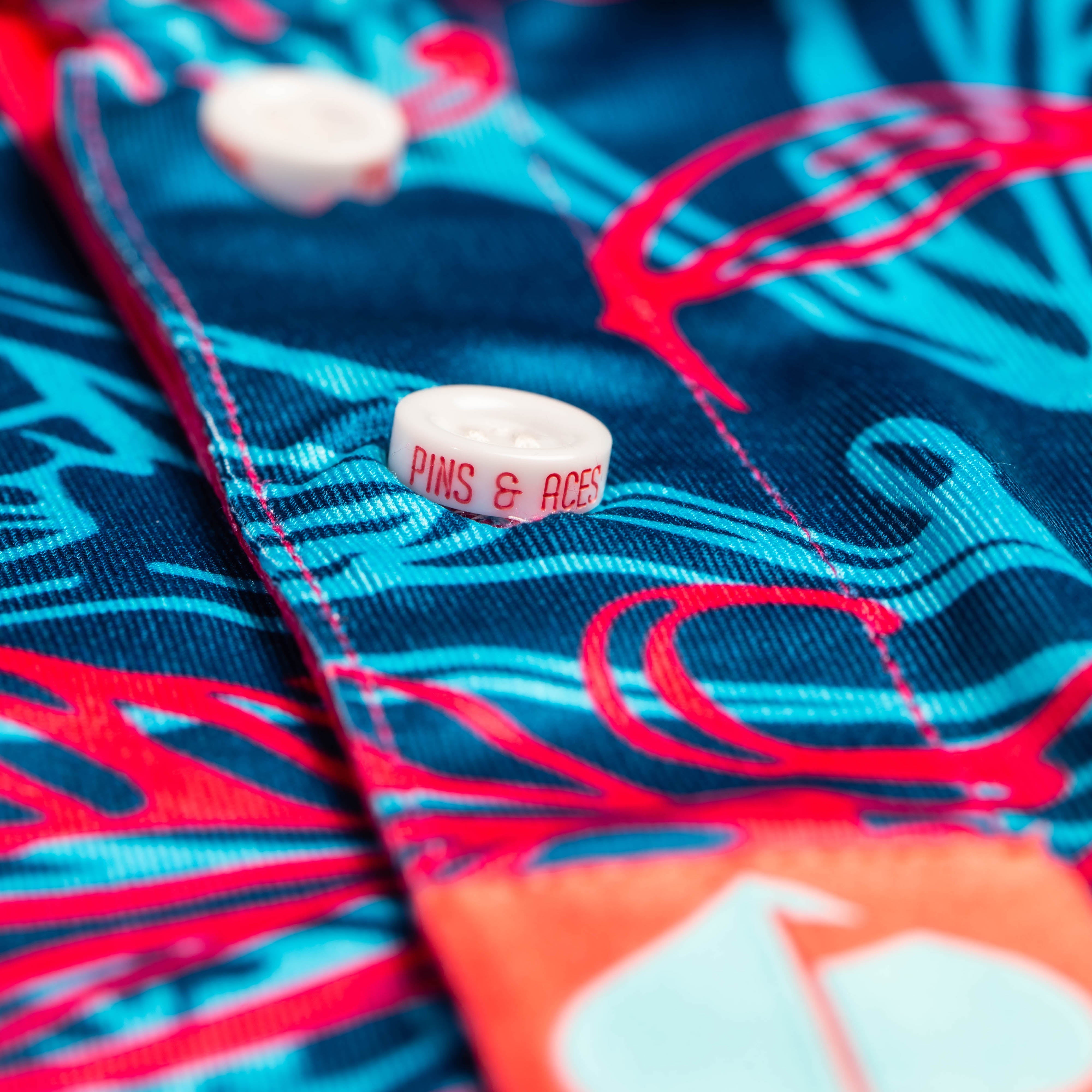 Blue and magenta Hawaiian polo shirt featuring vibrant tropical patterns and a relaxed fit.